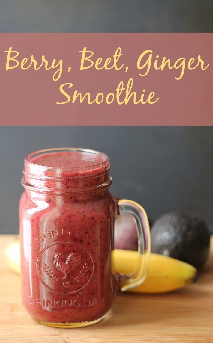 Berry Beet Ginger Smoothie in a clear glass sitting on a wooden table.