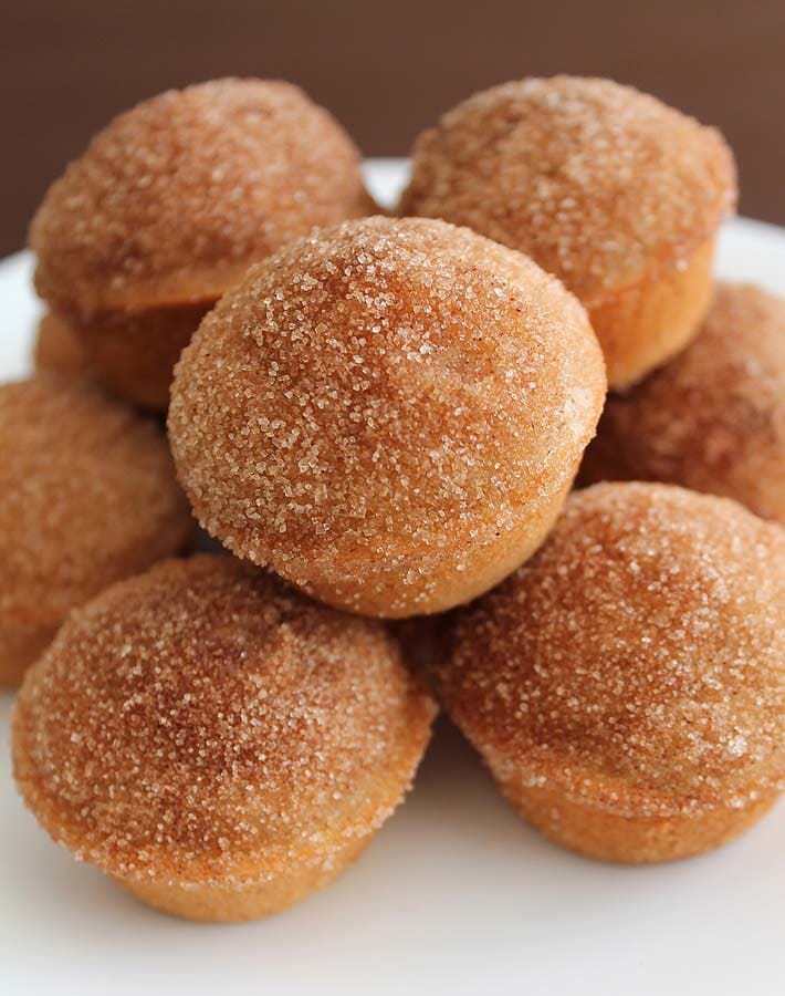 Ten Old Fashioned Cake Doughnut Mini Muffins on a white plate piled on top of each other.