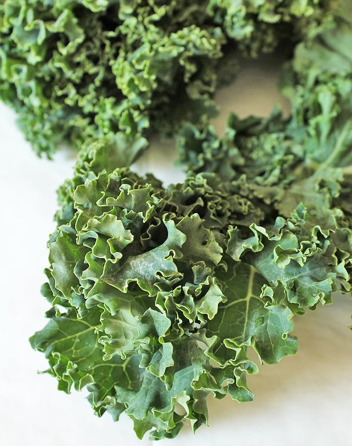 Raw kale leaves on a table to make easy kale chips.