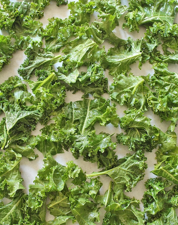 Raw kale leaves on a baking sheet to make Easy Kale Chips.