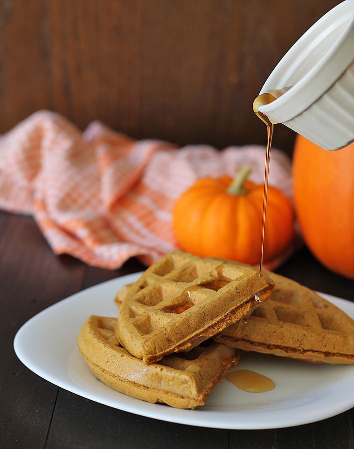 Maple syrup being poured on Vegan Gluten Free Pumpkin Spice Waffles.