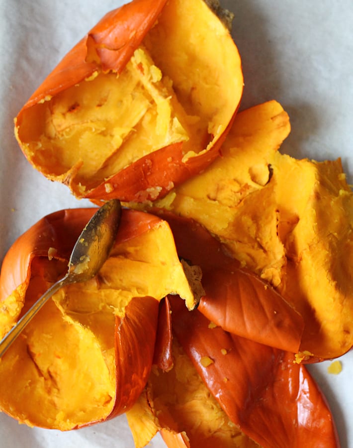How to Make Homemade Pumpkin Puree - Skins from sugar pumpkins lying on a baking sheet, insides have been scooped out.
