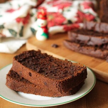 Vegan Gluten Free Gingerbread Loaf slices on a small plate, rest of the load sits in the background.