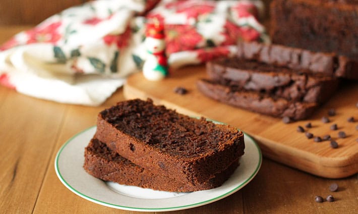 Vegan Gluten Free Gingerbread Loaf slices on a small plate, rest of the load sits in the background.
