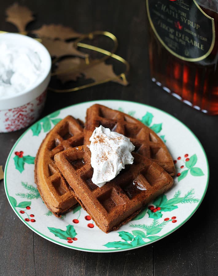 Vegan Gluten Free Gingerbread Waffles on a festive plate with coconut whipped cream on top.