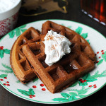 Vegan Gluten Free Gingerbread Waffles on a Christmas plate and coconut whipped cream on top.