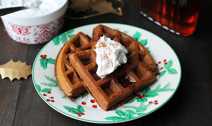 Vegan Gluten Free Gingerbread Waffles on a Christmas plate and coconut whipped cream on top.