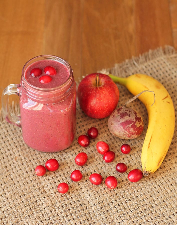 Cranberry Apple Smoothie and ingredients on a brown table.