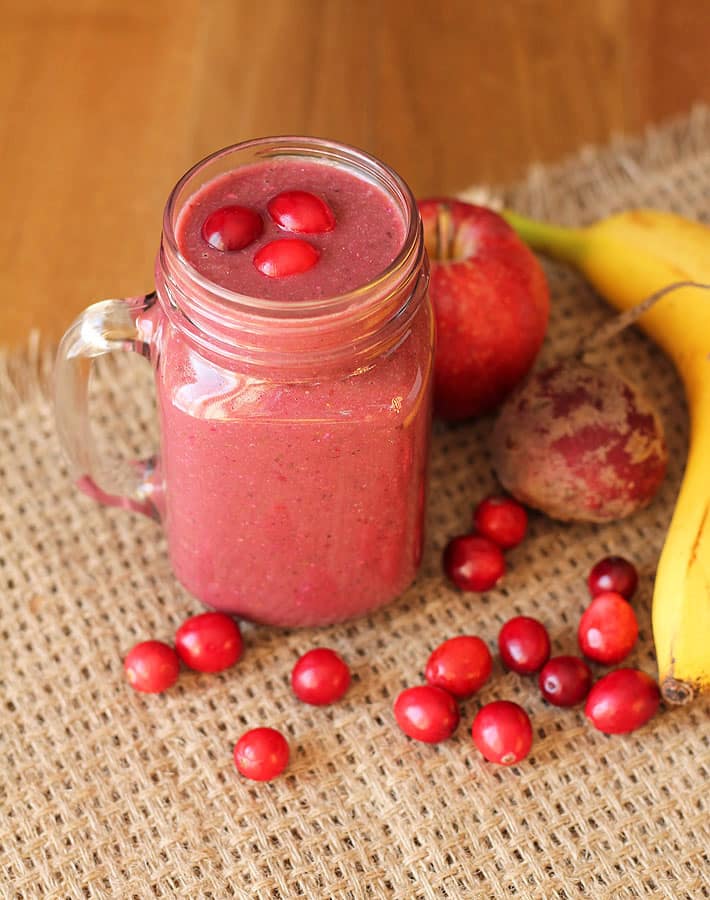 Cranberry Apple Smoothie in a glass mug with the ingredients sitting to the right of the mug.