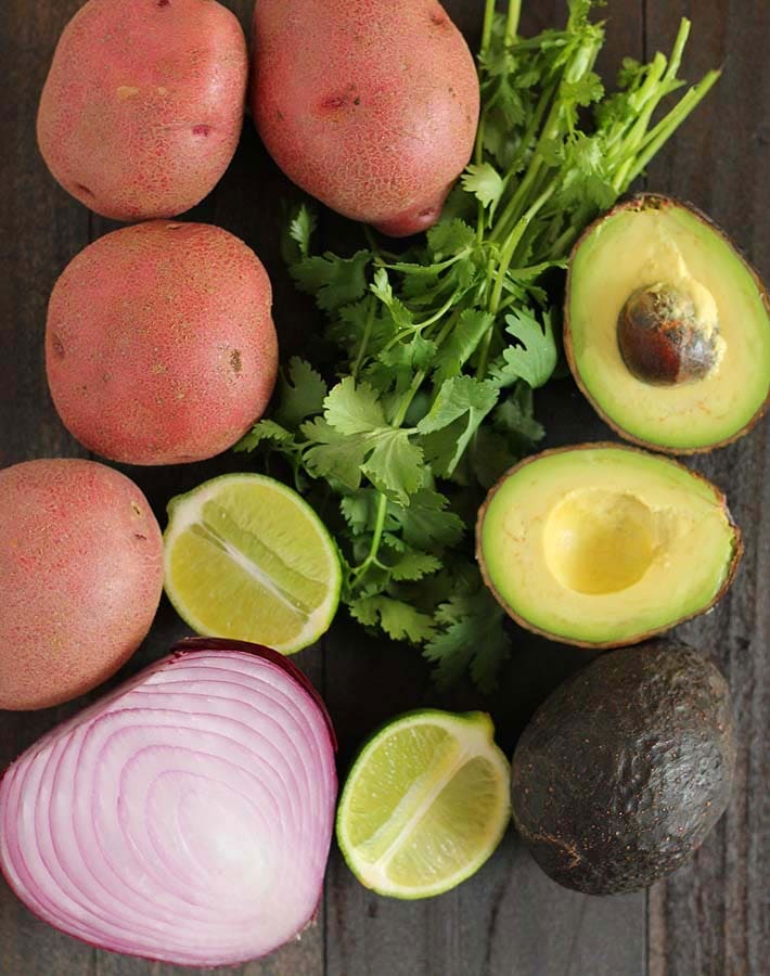 Overhead shot of some of the ingredients for a vegan breakfast burrito (red potatoes, cilantro, lime, avocado, red onion).