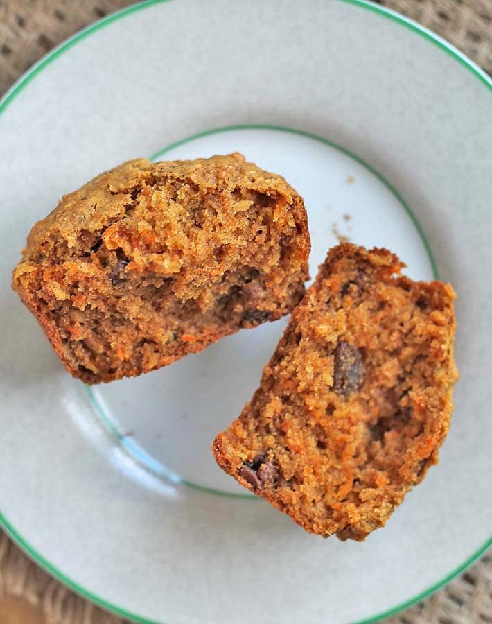 A carrot coconut muffin on a small plate split open to show the inner texture.