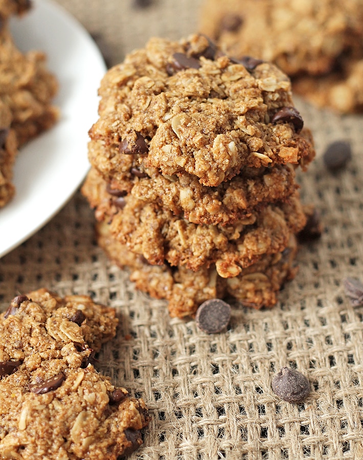 A stack of three chocolate chip coconut oatmeal cookies on a burlap placemat.