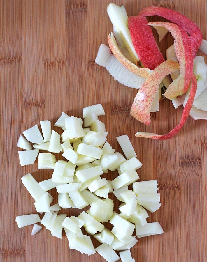 Freshly chopped apples on a bamboo cutting board that will be used to make apple cinnamon waffles.