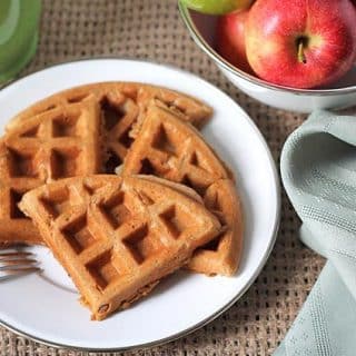 Apple cinnamon waffles on a white plate with a fork on the side of the plate.
