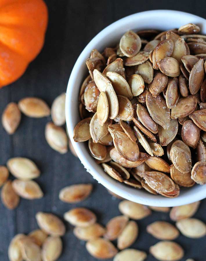 How to Roast Pumpkin Seeds - Overhead shot of roasted pumpkin seeds in a white bowl.