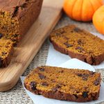 A loaf of Vegan Gluten Free Pumpkin Chocolate Chip Bread with three slices sliced out of it, two slices are sitting off to the side and two small pumpkins sitting behind it.