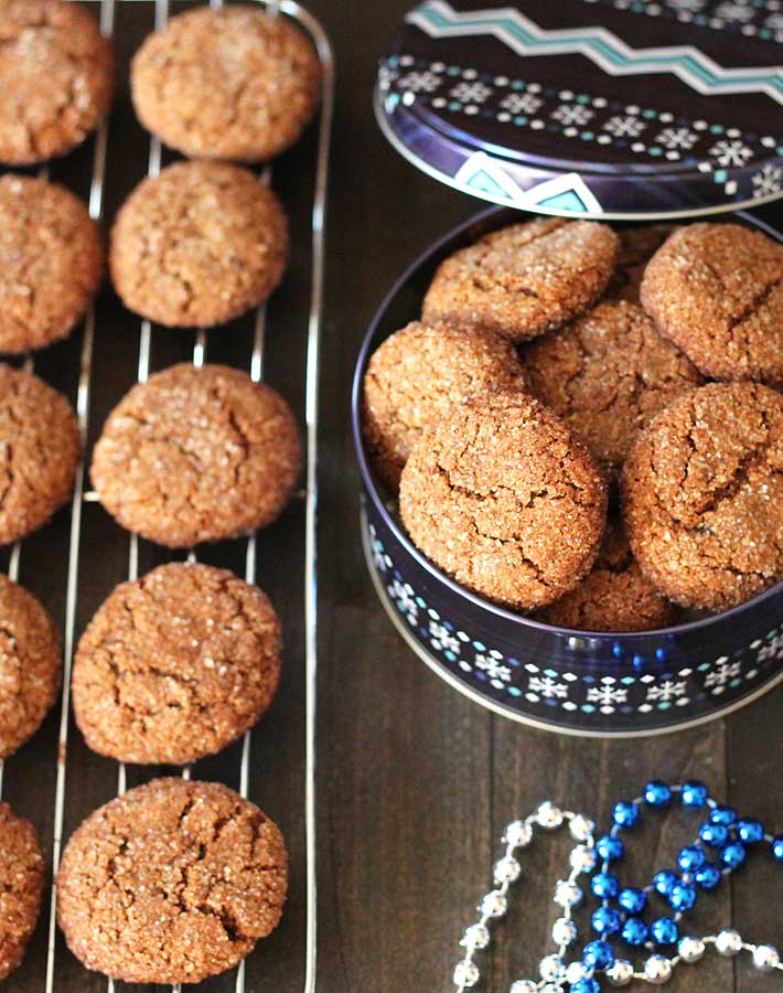 Vegan Gluten Free Gingerbread Cookies sitting in an opened tin with the lid leaning up to it on the back.