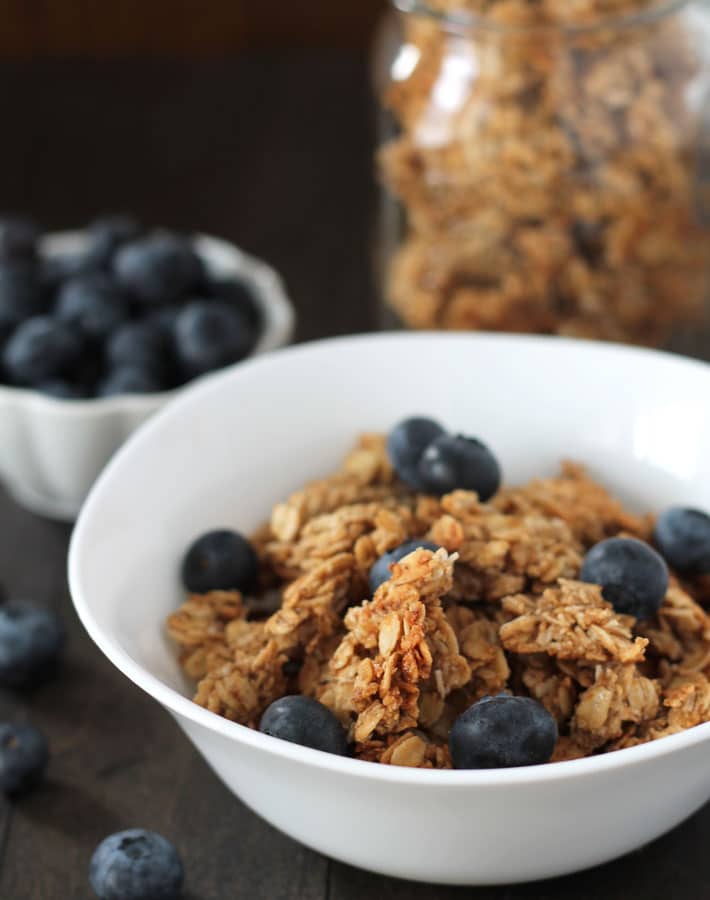 A bowl of nut free granola with fresh blueberries on top.