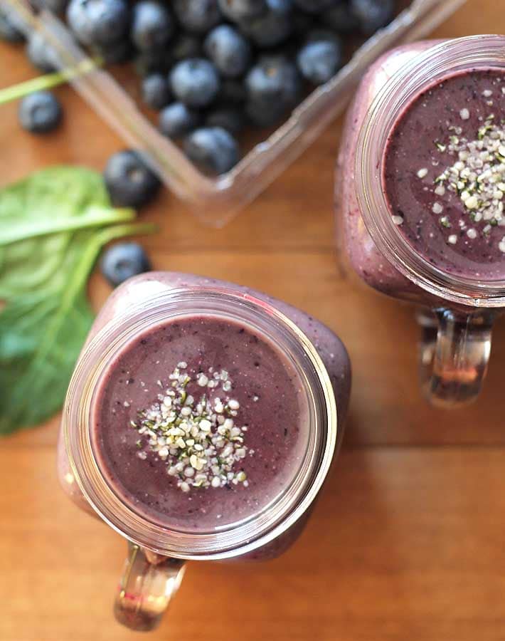 Overhead shot of a glass of Blueberry Pineapple Smoothie, hemp hearts are sprinkled on top of the smoothie.