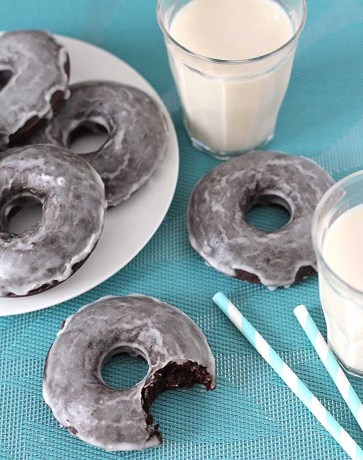 Chocolate glazed doughnuts sitting next to a glass of milk.