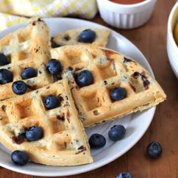 Four pieces of Vegan Gluten Free Lemon Blueberry Waffles on a plate.