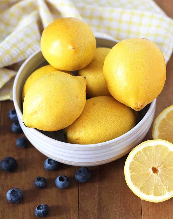 Fresh lemons and blueberries on a wood table to be used to make Vegan Gluten Free Lemon Blueberry Waffles.