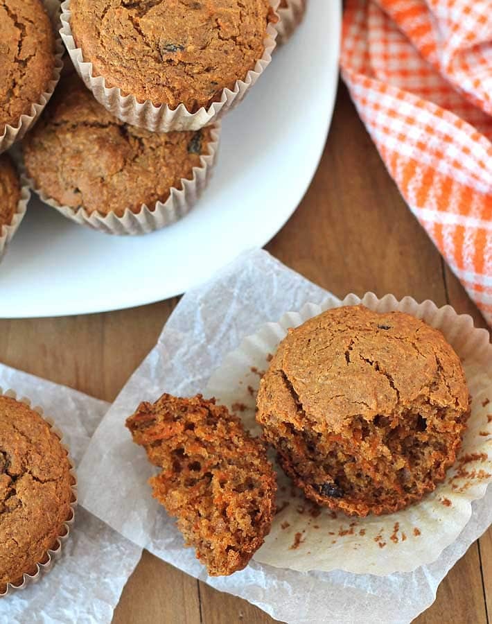 Overhead shot of Carrot Ginger Muffins on a white plate, two muffins are off the plate and on the table.