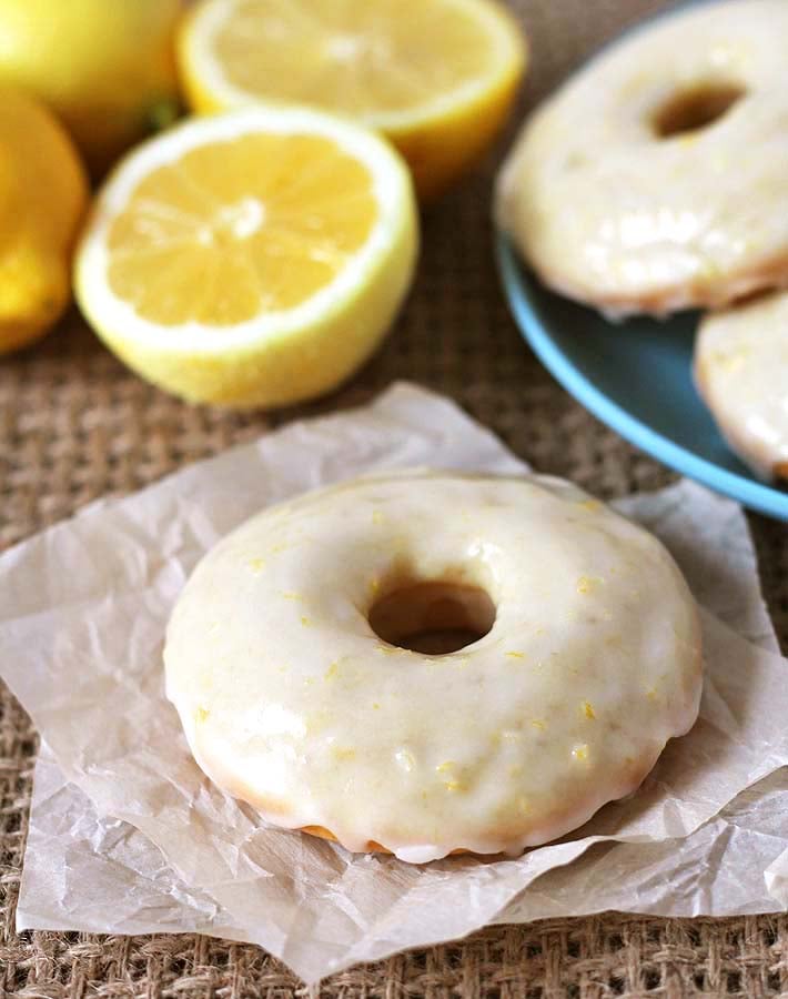 A vegan lemon doughnut on a square piece of parchment paper.