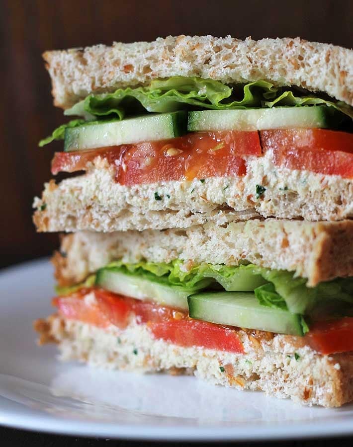 Garlic herb vegan almond cheese spread on a veggie sandwich.