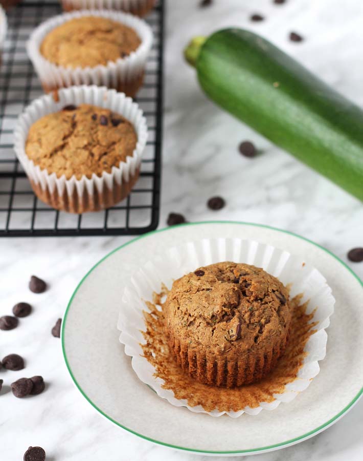 Vegan Gluten Free Zucchini Chocolate Chip Muffins sitting on a cooling rack and on a plate.