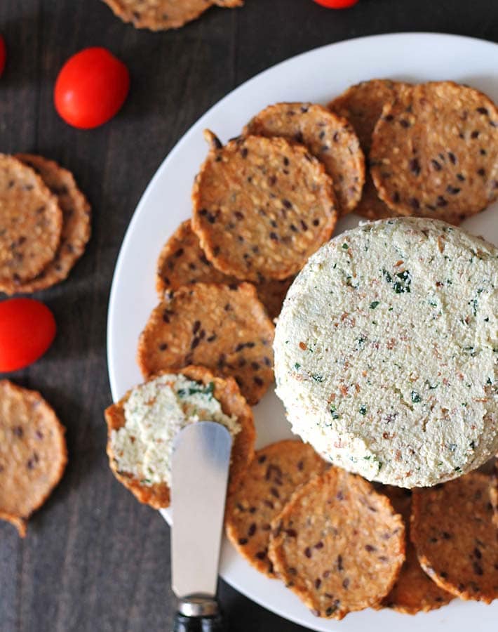 Garlic herb vegan almond cheese spread sitting on a plate with crackers.