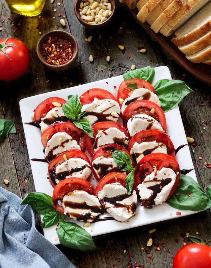 Vegan mozzarella cheese sitting on a plate with sliced tomatoes
