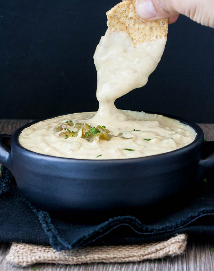 Vegan Queso Blanco (Mexican White Cheese Dip) in a bowl being scooped out with a chip.