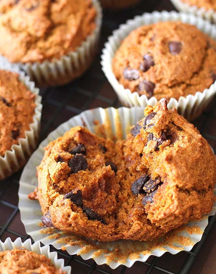 Vegan Gluten Free Pumpkin Spice Muffins sitting on a baking cooling rack with one muffin split open