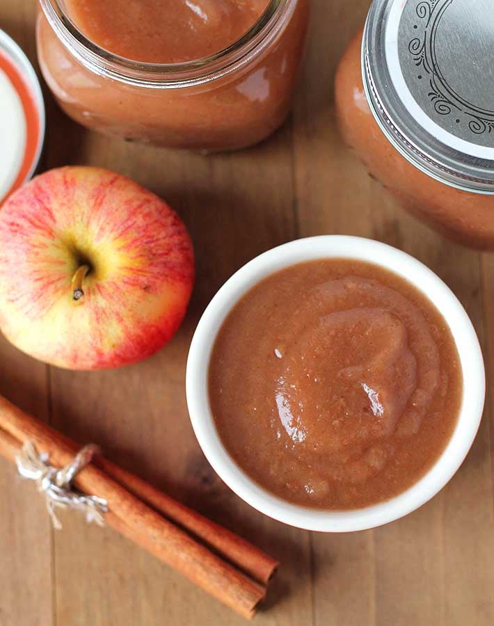 Overhead shot of slow cooker applesauce in a small bowl sitting on a wood table