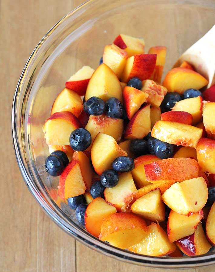 A bowl of freshly chopped peaches and whole blueberries about to be used to make a Vegan Peach Blueberry Crisp