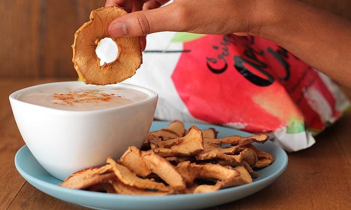 Vegan Snack Ideas for Active Kids plus an Easy Yogurt Dip Recipe: A child's hand dipping an apple chip into a bowl of yogurt dip.