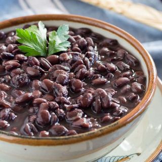 Easy Instant Pot Vegan Recipes - Cooked Instant Pot black beans in a bowl with a sprig of cilantro on top of the beans.