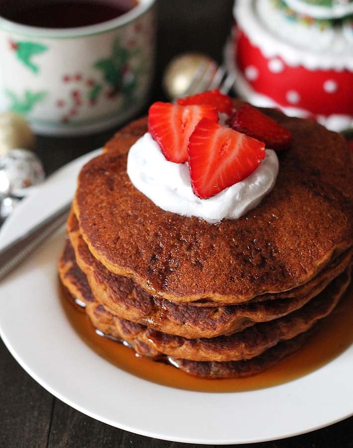 Four Gluten Free Vegan Gingerbread Pancakes on a white plate with a fork sitting on the left side of the plate.