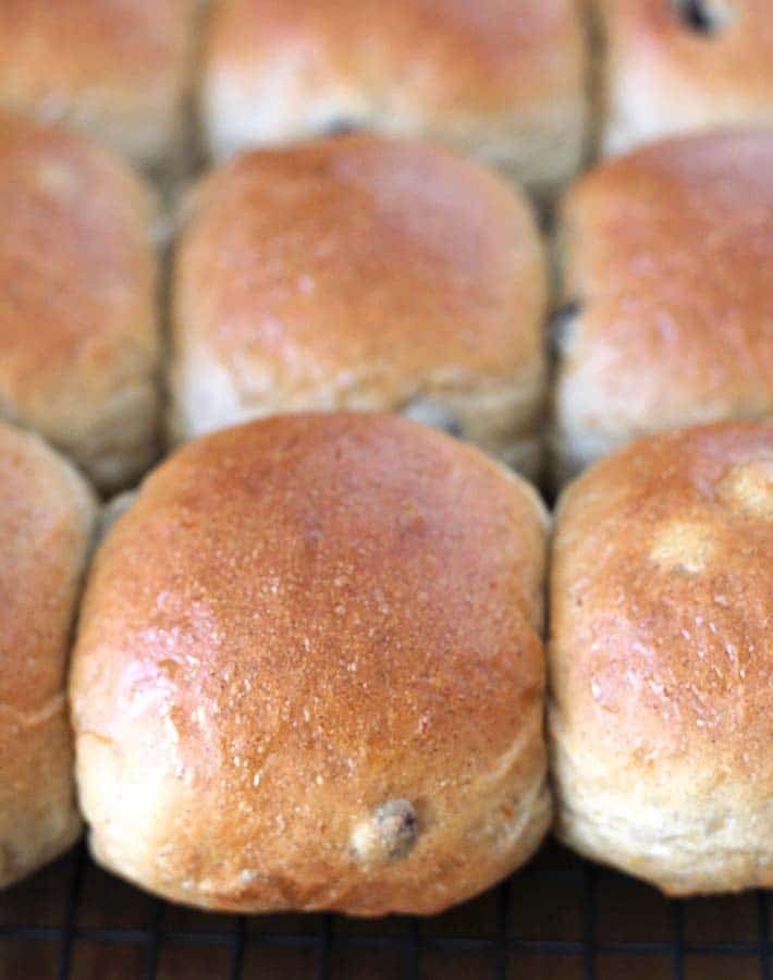 Fresh rolls just out of the oven on a cooling rack that were brushed with a vegan egg wash before baking so they are golden on top.