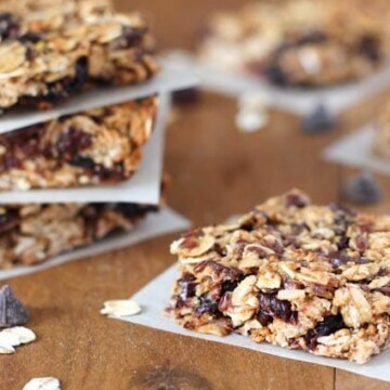 Vegan granola bars on individual parchment squares sitting on a brown wooden table.