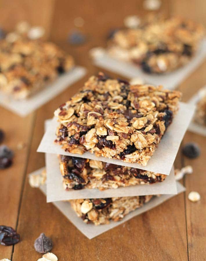 A stack of three vegan granola bars sitting on a brown wood table.