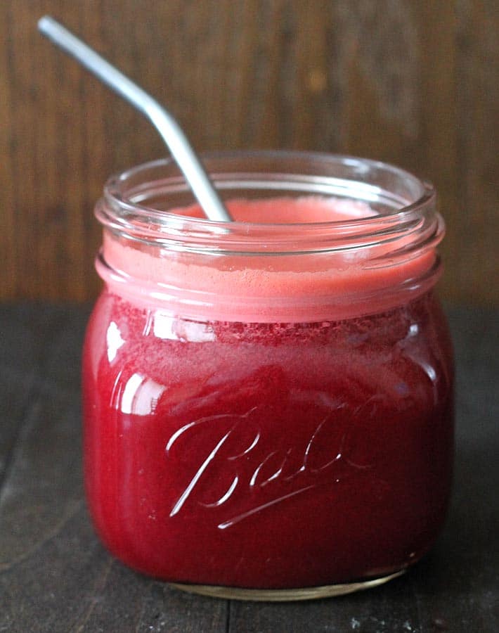 Beet Carrot Apple Juice in a Ball Mason jar with a stainless steel straw in the jar.