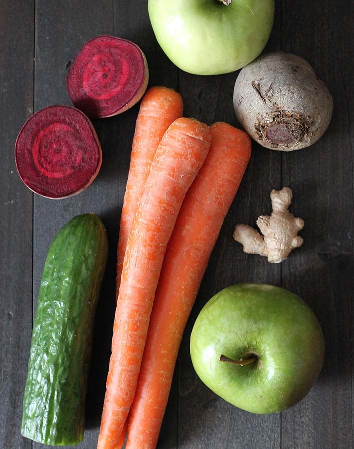 Ingredients for Beet Carrot Apple Juice on a dark wood table.