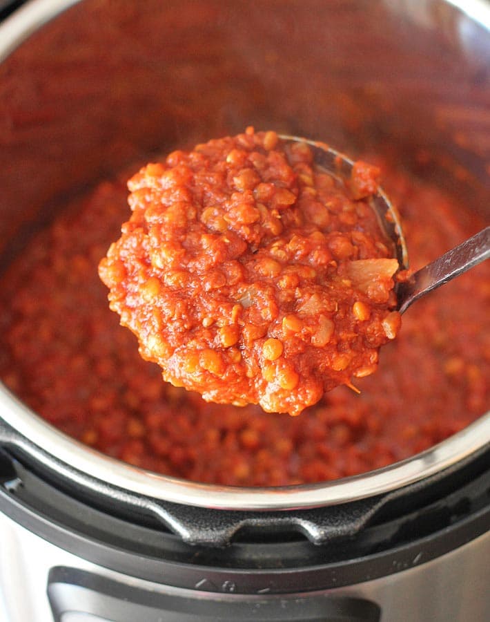 Finished filling for lentil sloppy joes sandwiches being scooped from a ladle out of an Instant Pot.