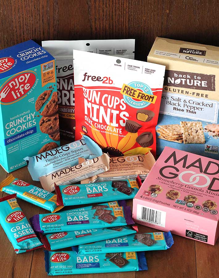 An assortment of packaged store-bought, allergy-friendly, nut-free snacks on a wood table.
