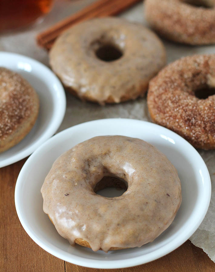 Chai-Spiced Baked Vegan Doughnuts on plates, more doughnuts sits to the the right of the plates.