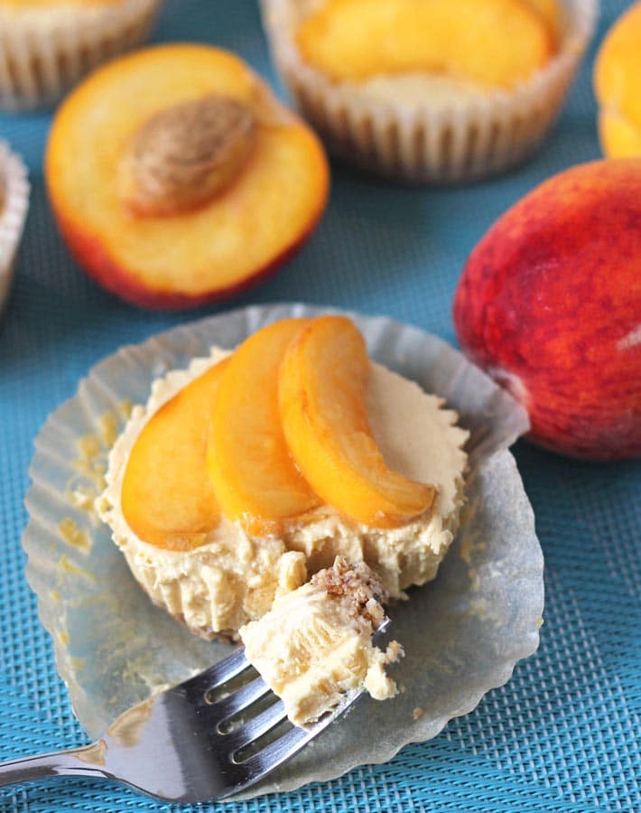 Vegan No Bake Peach Cheesecake bites on a blue placemat, one bite has a forkful taken out of it.
