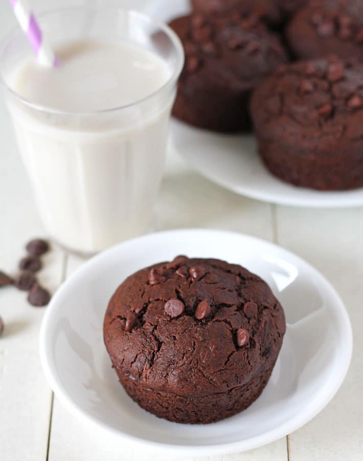 Vegan Gluten Free Chocolate Zucchini Muffins on white plates sitting on a white wooden table.