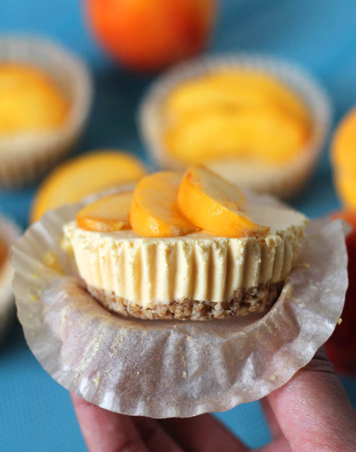 A No Bake Peach Cheesecake bite being held up by a hand to show a close-up.